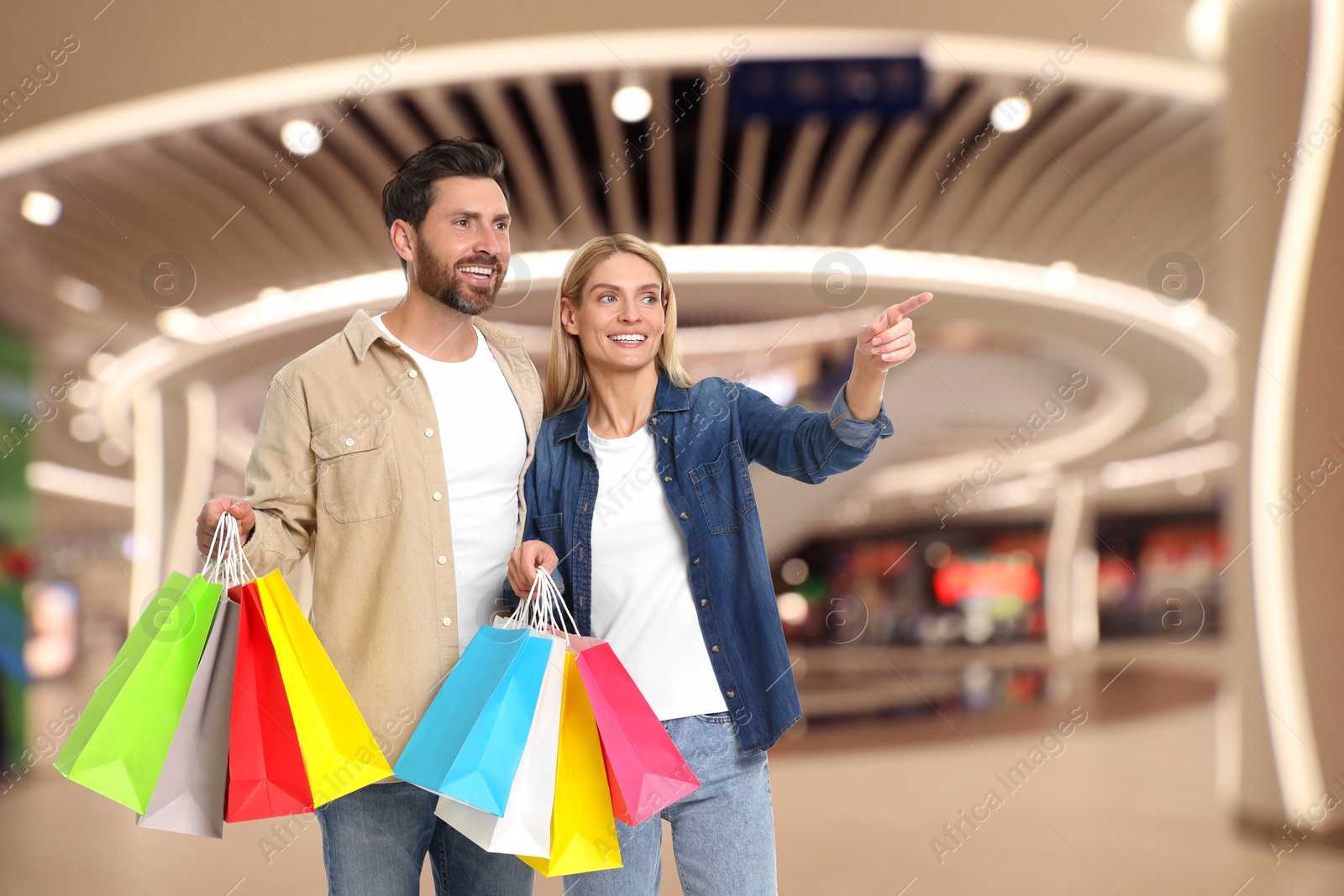 Image of Happy couple with shopping bags walking in mall