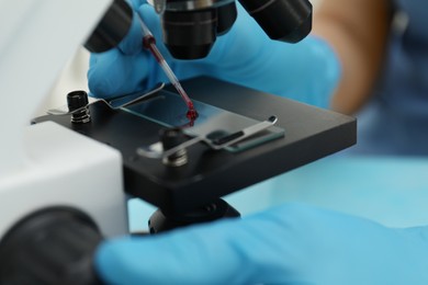 Photo of Doctor with blood sample from finger at table in laboratory, closeup