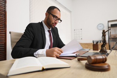 Photo of Confident lawyer working with document at table in office