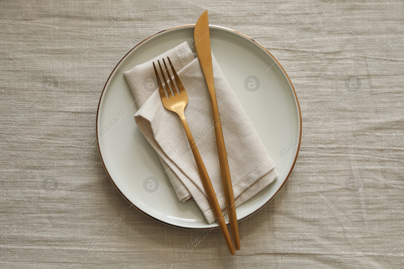 Photo of Stylish setting with cutlery, napkin and plate on light table, top view