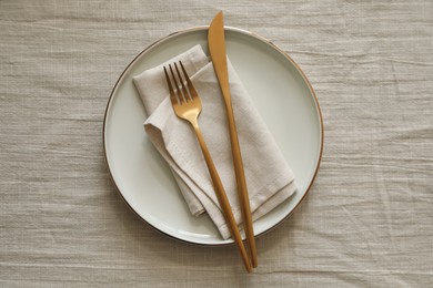 Stylish setting with cutlery, napkin and plate on light table, top view