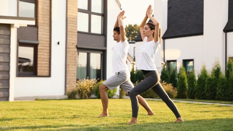 Photo of Sporty couple practicing morning yoga at backyard. Healthy lifestyle