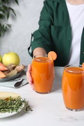 Woman taking glass with carrot juice, closeup