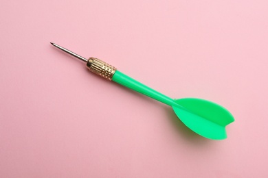 Photo of Green dart arrow on pink background, top view