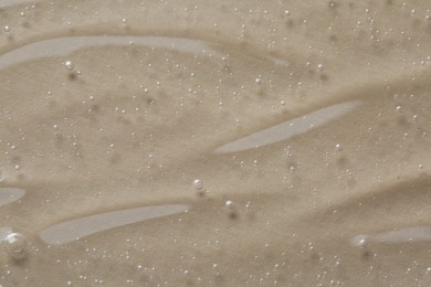 Photo of Clear cosmetic serum on beige background, macro view