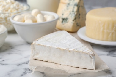 Photo of Brie cheese and other dairy products on table, closeup