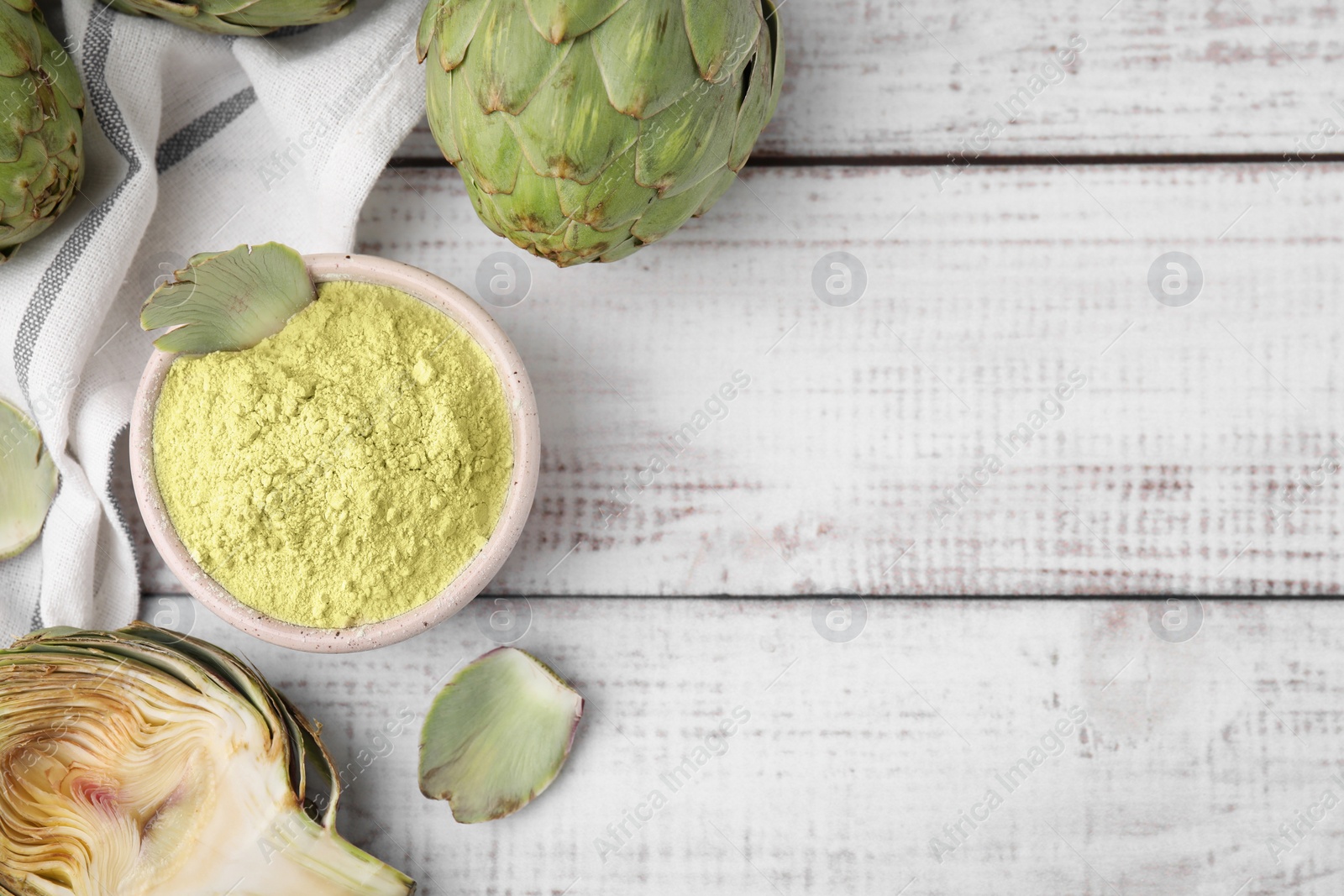 Photo of Bowl with powder and fresh artichokes on white wooden table, flat lay. Space for text