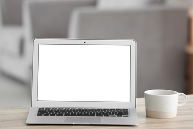 Laptop with blank screen on table indoors. Space for text