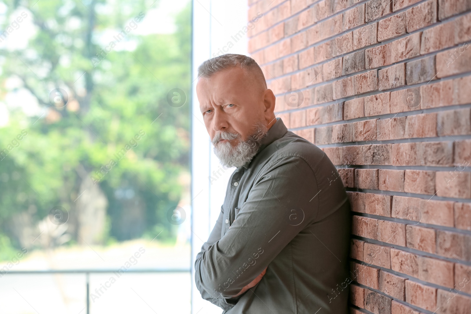 Photo of Senior man in state of depression near brick wall