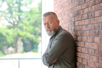 Senior man in state of depression near brick wall