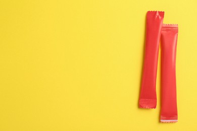 Red sticks of sugar on yellow background, flat lay. Space for text