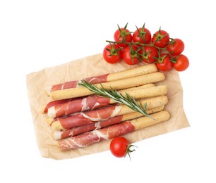 Delicious grissini sticks with prosciutto, tomatoes and rosemary on white background, top view