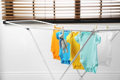 Different cute baby onesies and toy bear hanging on clothes line. Laundry day