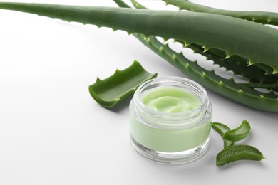 Jar of natural cream and aloe leaves on white background. Space for text