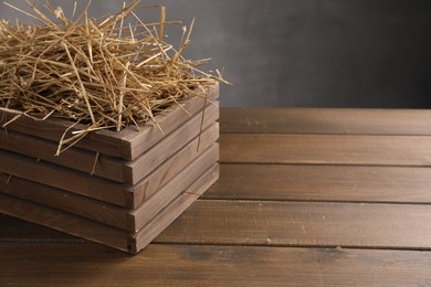 Dried straw in crate on wooden table, space for text