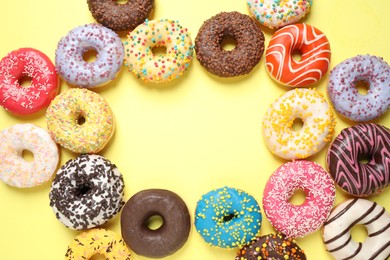 Delicious glazed donuts on yellow background, flat lay. Space for text