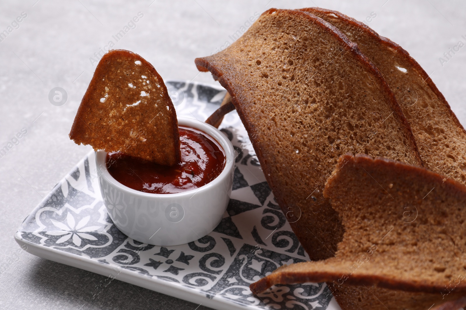 Photo of Plate with crispy rusks and dip sauce on light table, closeup