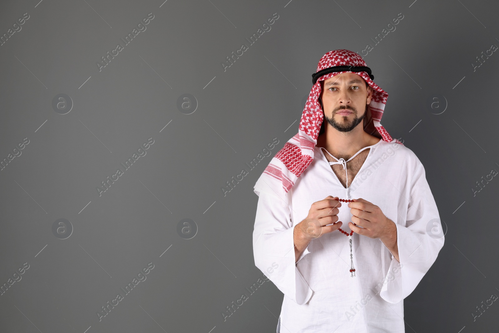 Photo of Muslim man praying on gray background. Space for text