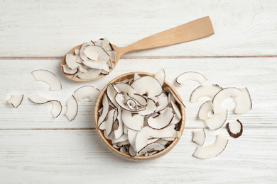 Photo of Tasty coconut chips on white wooden table, flat lay