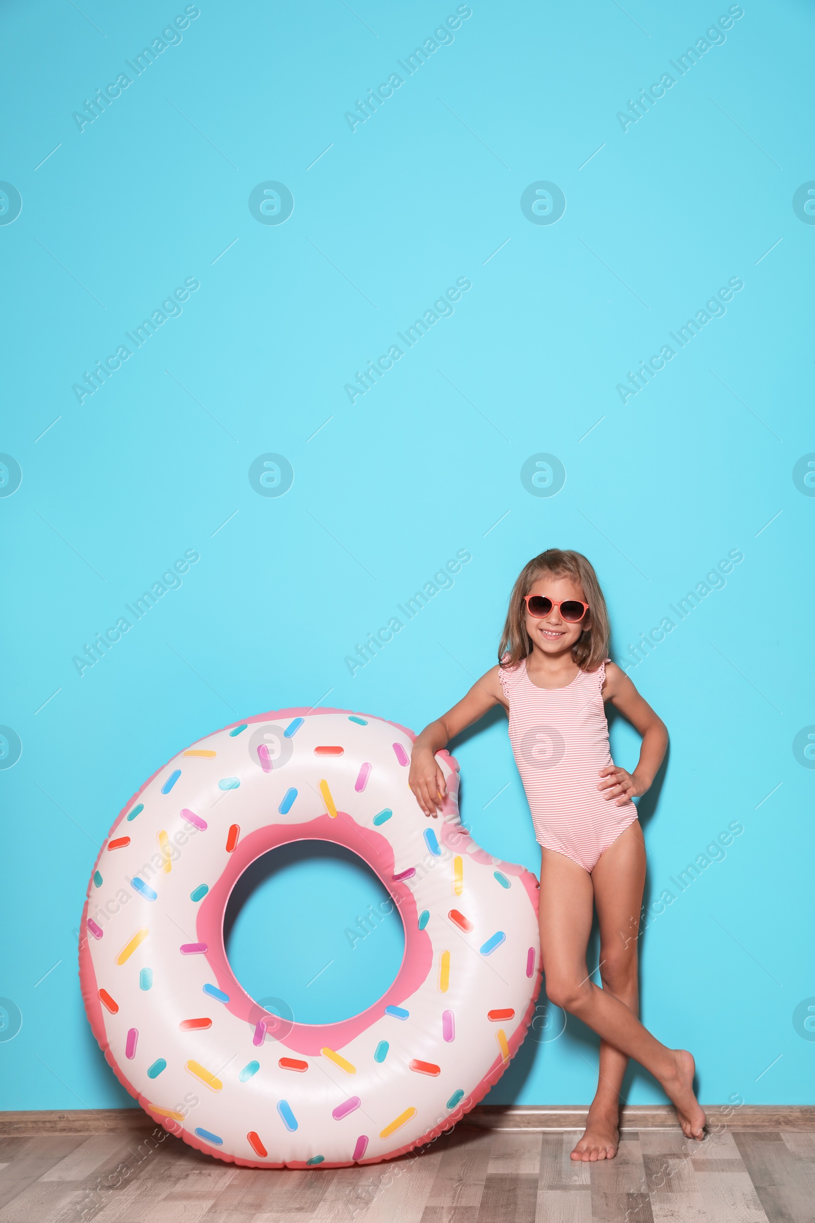 Photo of Cute little girl with bright inflatable ring near color wall