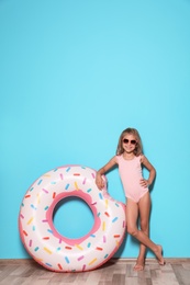 Cute little girl with bright inflatable ring near color wall