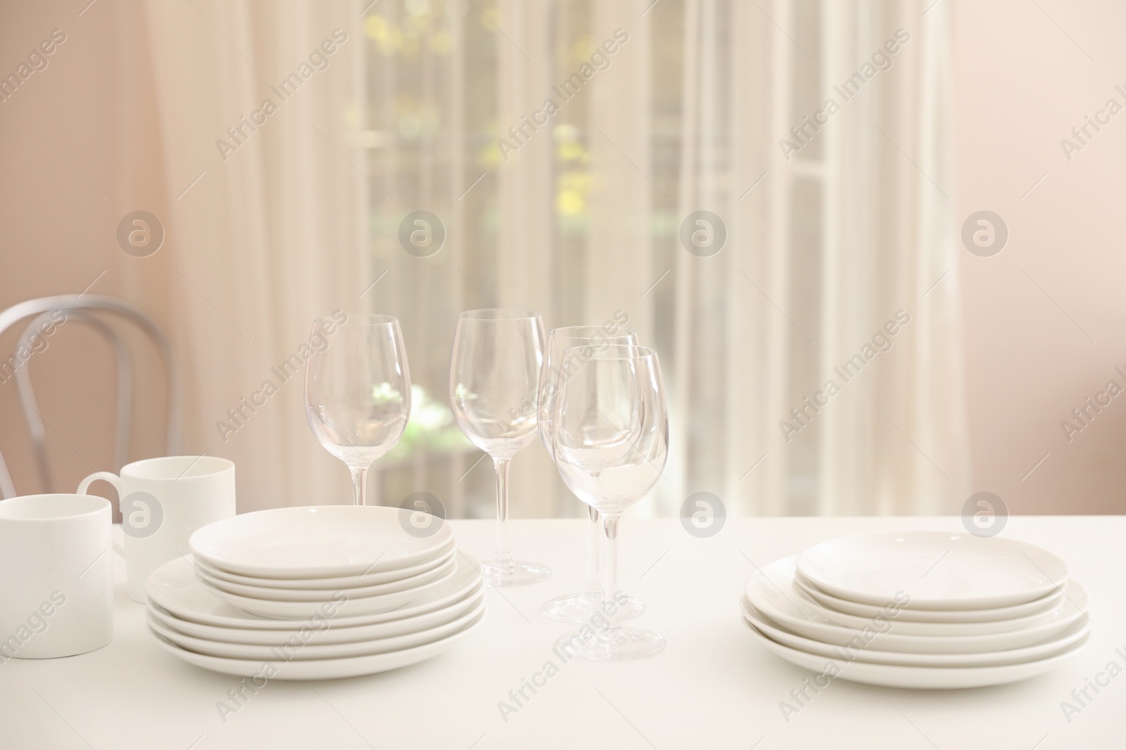 Photo of Stack of clean dishes, glasses and cups on table in kitchen