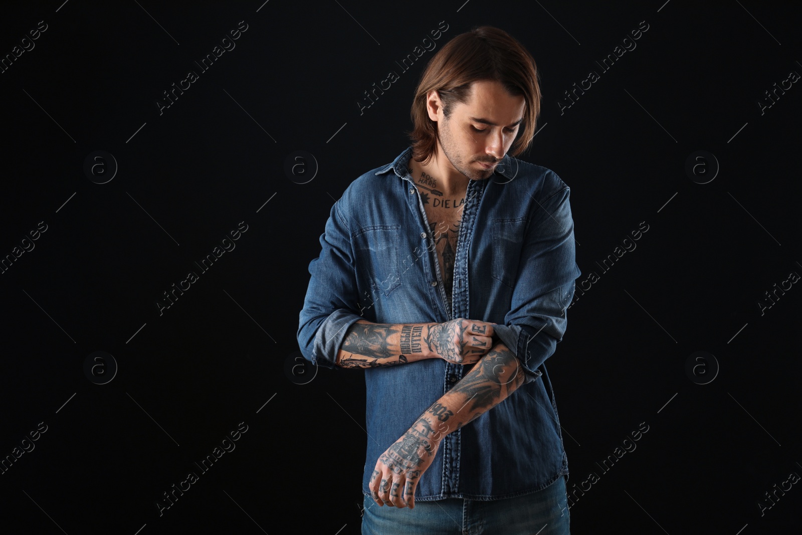 Photo of Young man with tattoos on body against black background