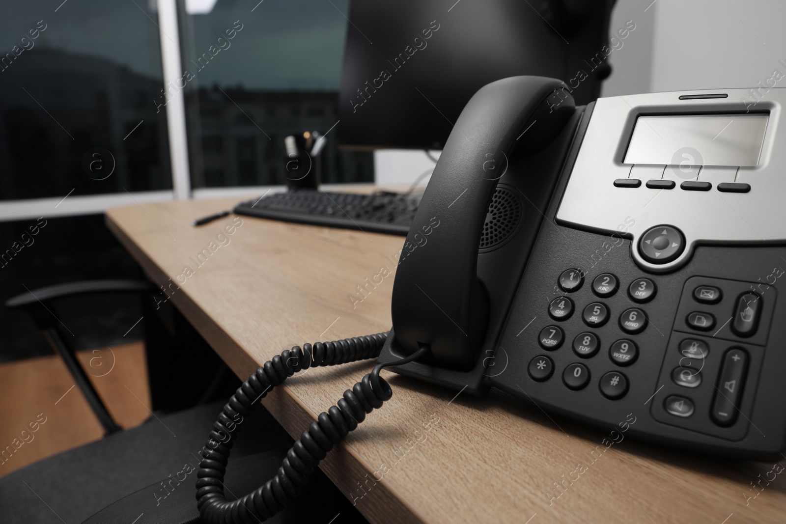 Photo of Stationary phone on wooden desk in office, closeup. Hotline service