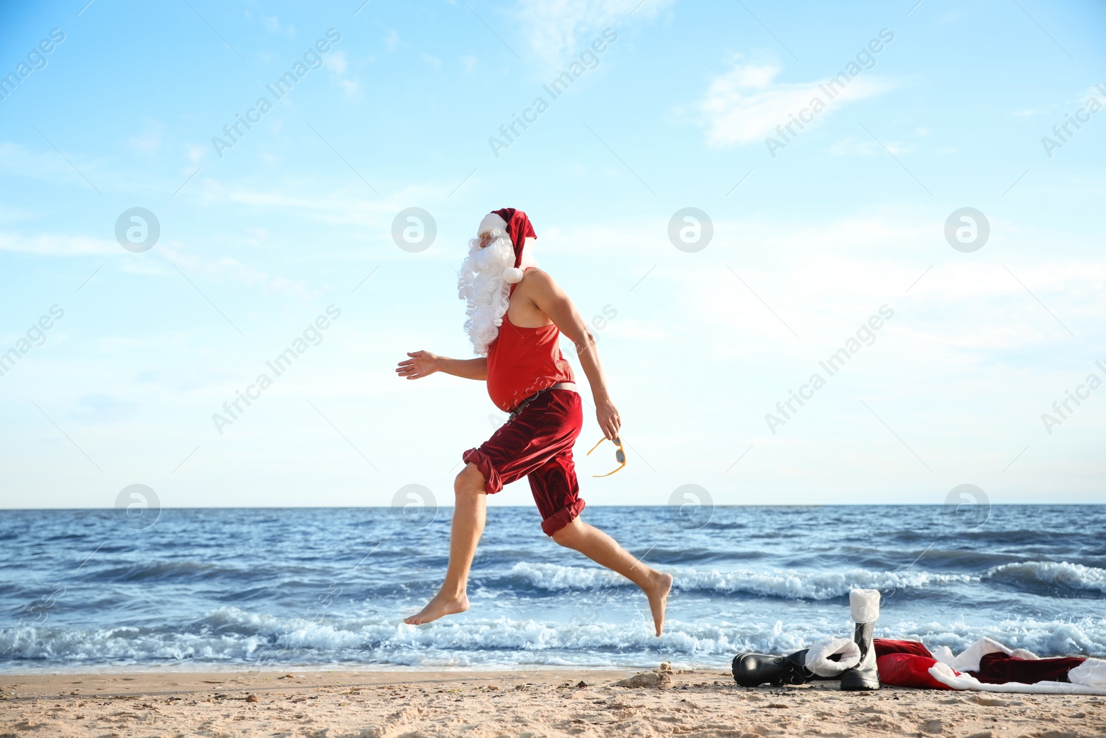 Photo of Santa Claus having fun on beach. Christmas vacation