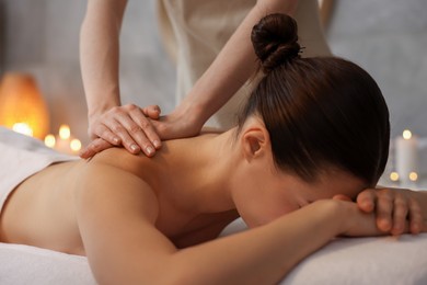 Photo of Woman receiving back massage on couch in spa salon