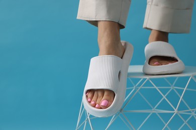 Photo of Woman wearing comfortable rubber slippers on light blue background, closeup. Space for text