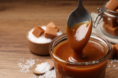 Taking tasty salted caramel with spoon from glass, closeup. Space for text