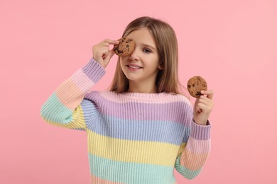 Photo of Cute girl with chocolate chip cookies on pink background
