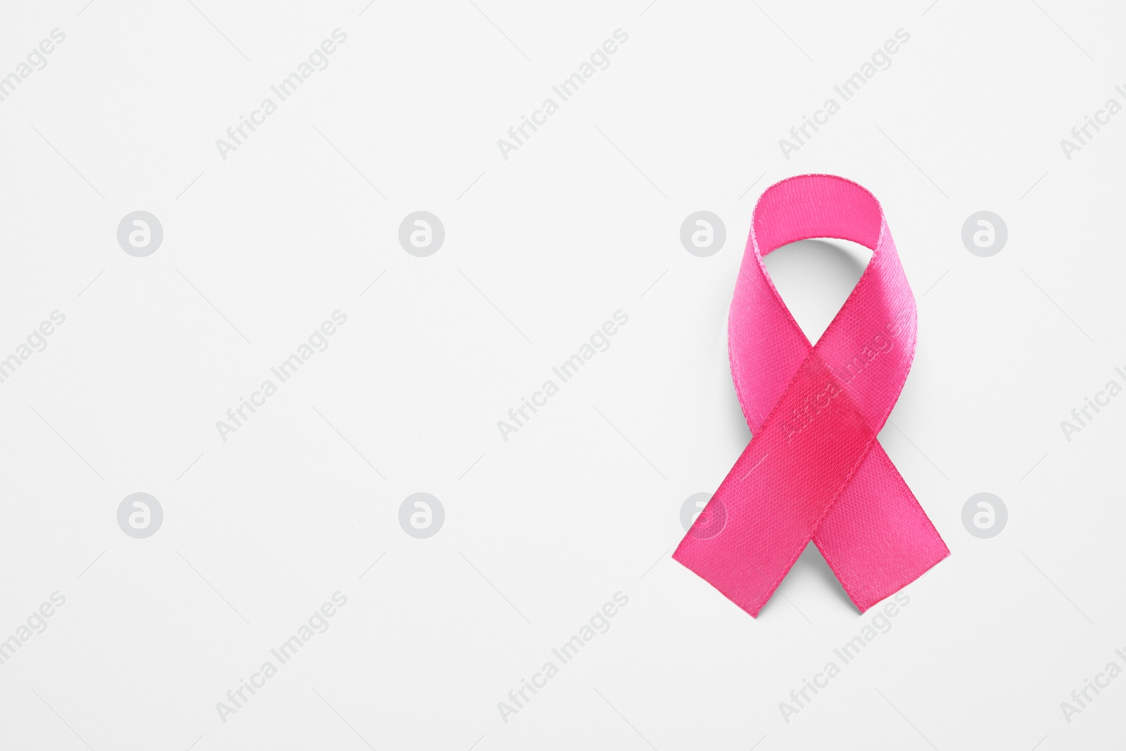 Photo of Pink ribbon on white background, top view and space for text. Breast cancer awareness