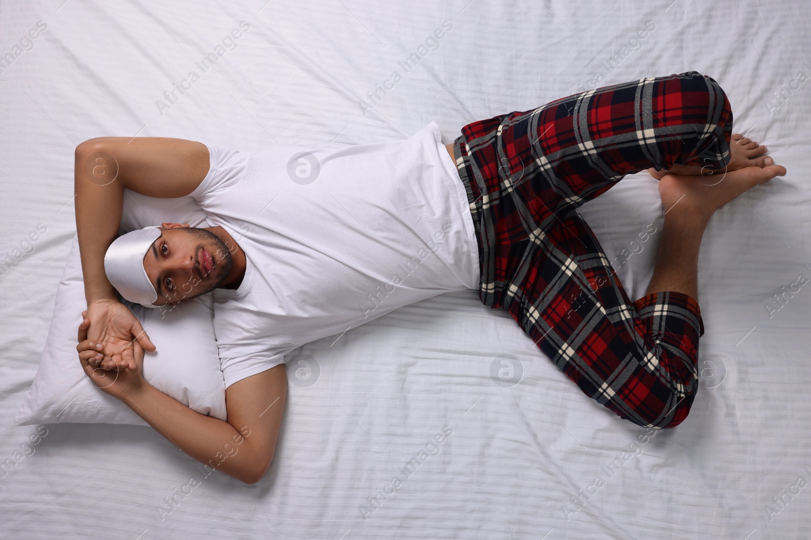 Photo of Man suffering from insomnia on bed, top view