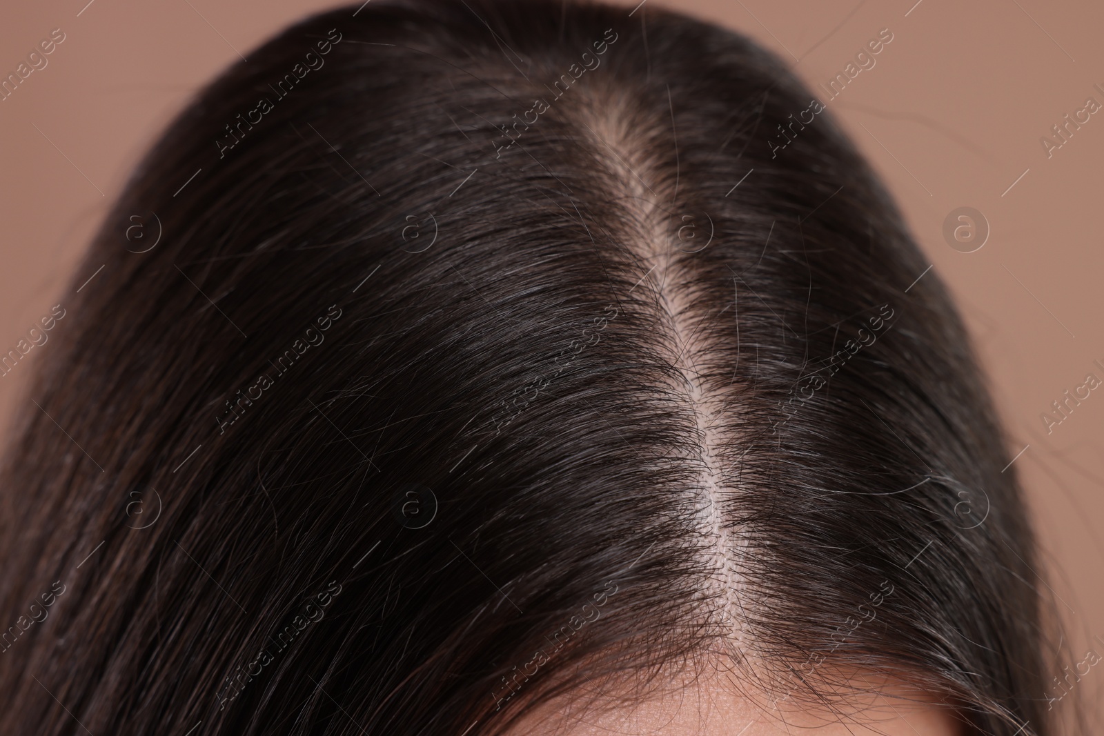 Photo of Woman with healthy dark hair on beige background, closeup