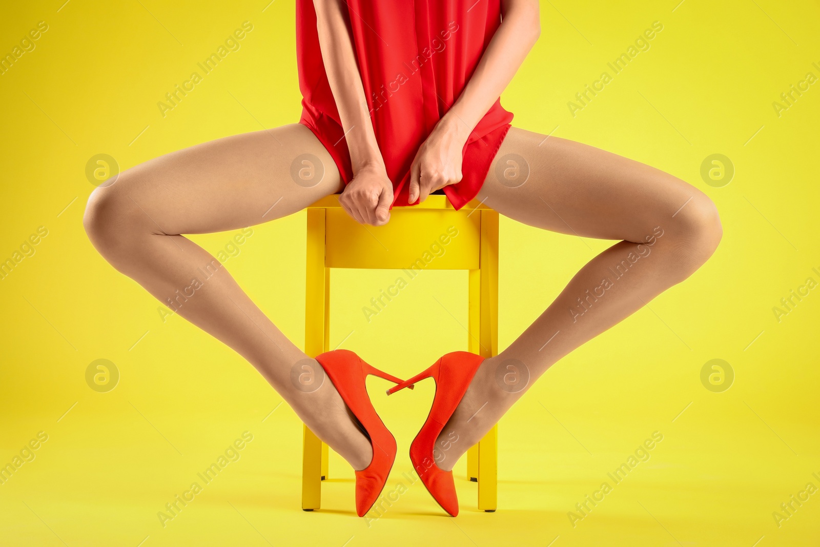 Photo of Woman wearing tights and stylish red shoes on yellow background, closeup