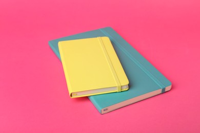 Photo of New stylish colorful planners on pink background