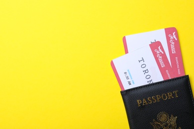 Photo of Passport with avia tickets on yellow background, top view and space for text. Travel agency concept