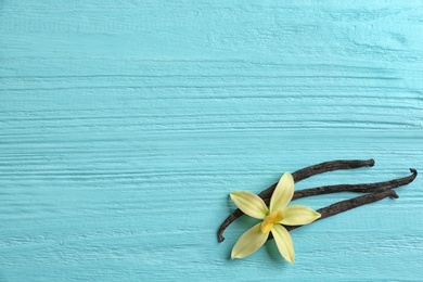 Photo of Flat lay composition with vanilla sticks and flower on wooden background. Space for text