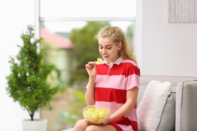 Photo of Woman eating potato chips in living room. Space for text