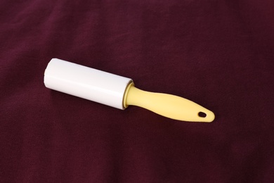 Photo of New lint roller with yellow handle on red fabric