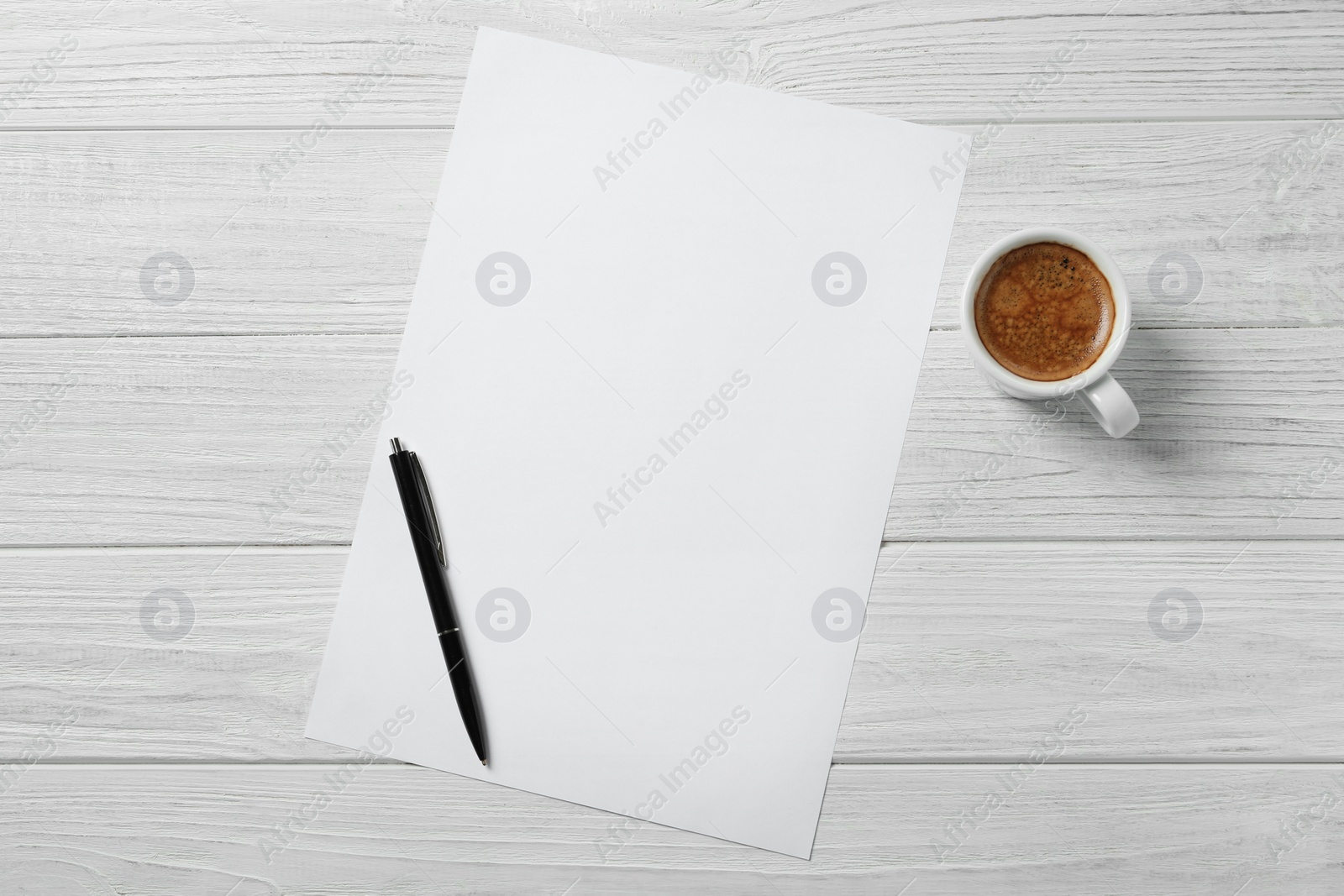 Photo of Blank paper sheet, pen and cup of coffee on white wooden table, flat lay. Space for text