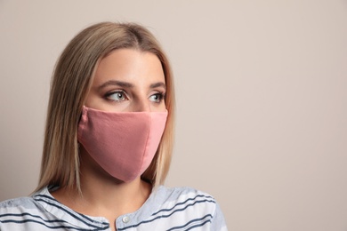 Photo of Young woman in protective face mask on beige background. Space for text