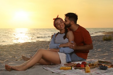 Lovely couple having picnic on sandy beach near sea