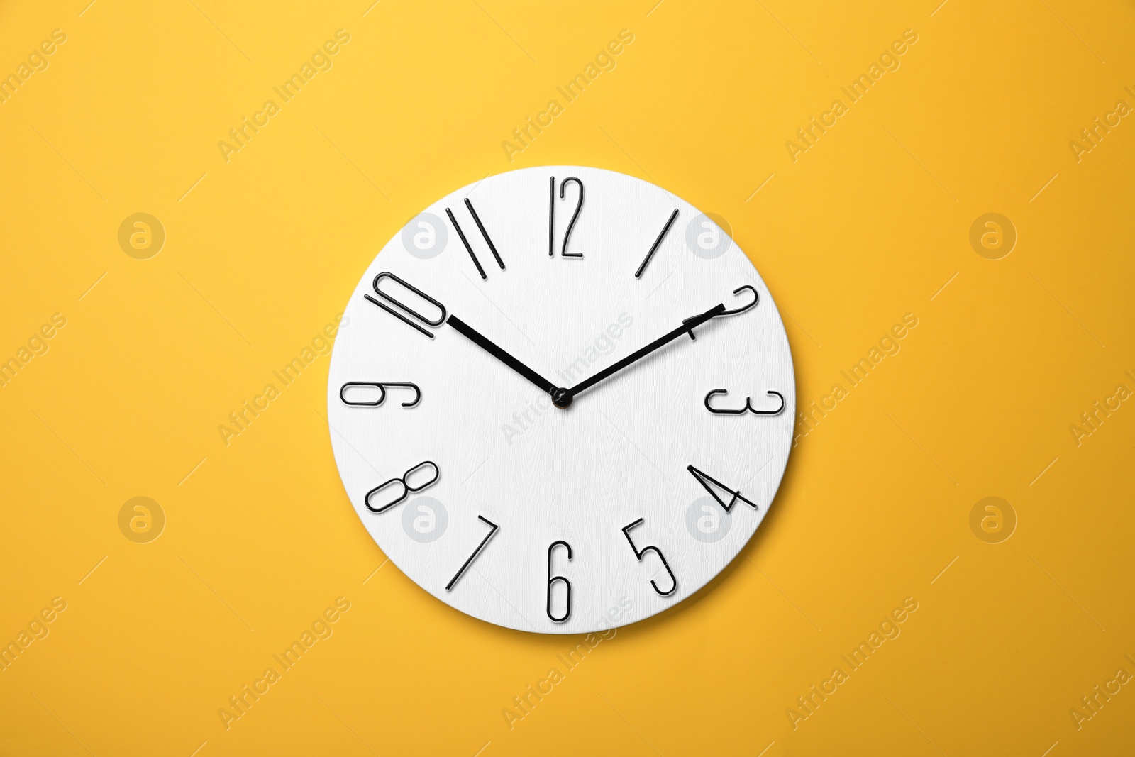 Photo of Modern clock on yellow background, top view