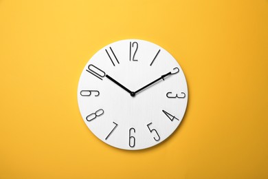 Modern clock on yellow background, top view