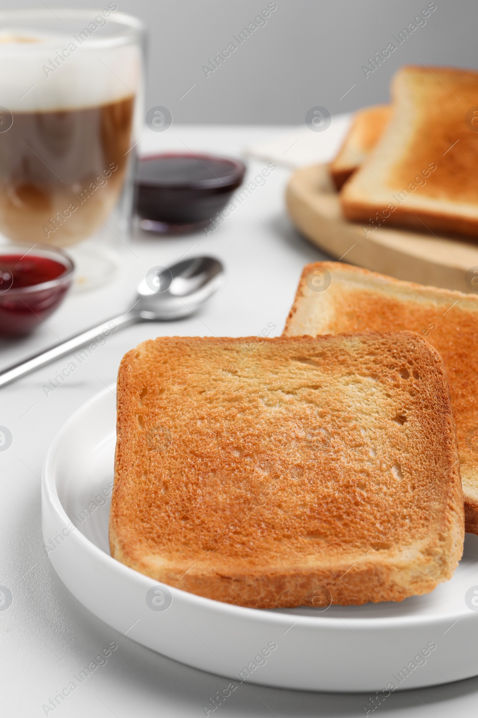 Photo of Slices of tasty toasted bread on white table, closeup