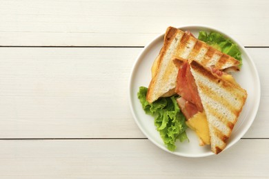 Tasty sandwiches with ham, lettuce and melted cheese on white wooden table, top view. Space for text