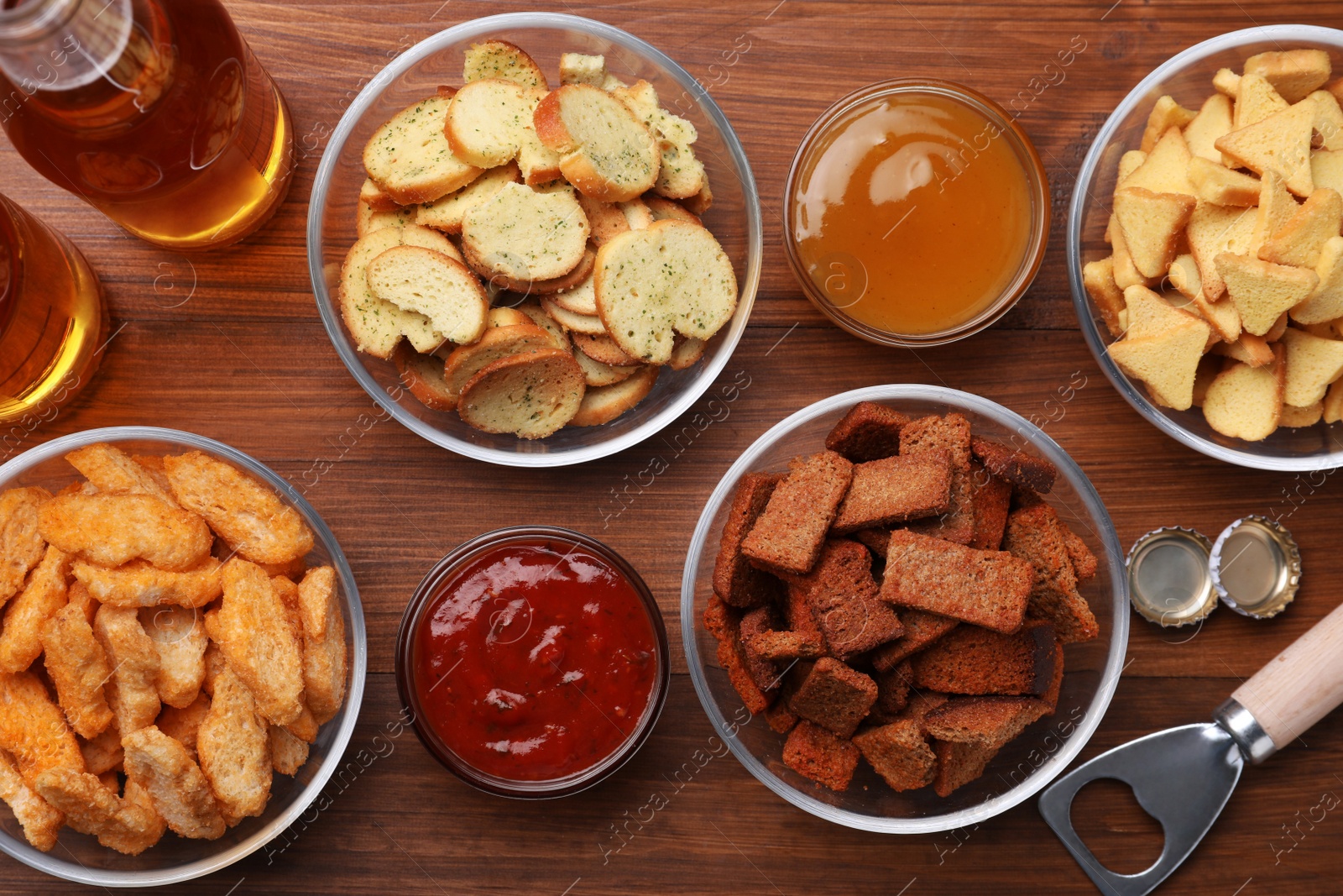 Photo of Different crispy rusks, beer and dip sauces on wooden table, flat lay